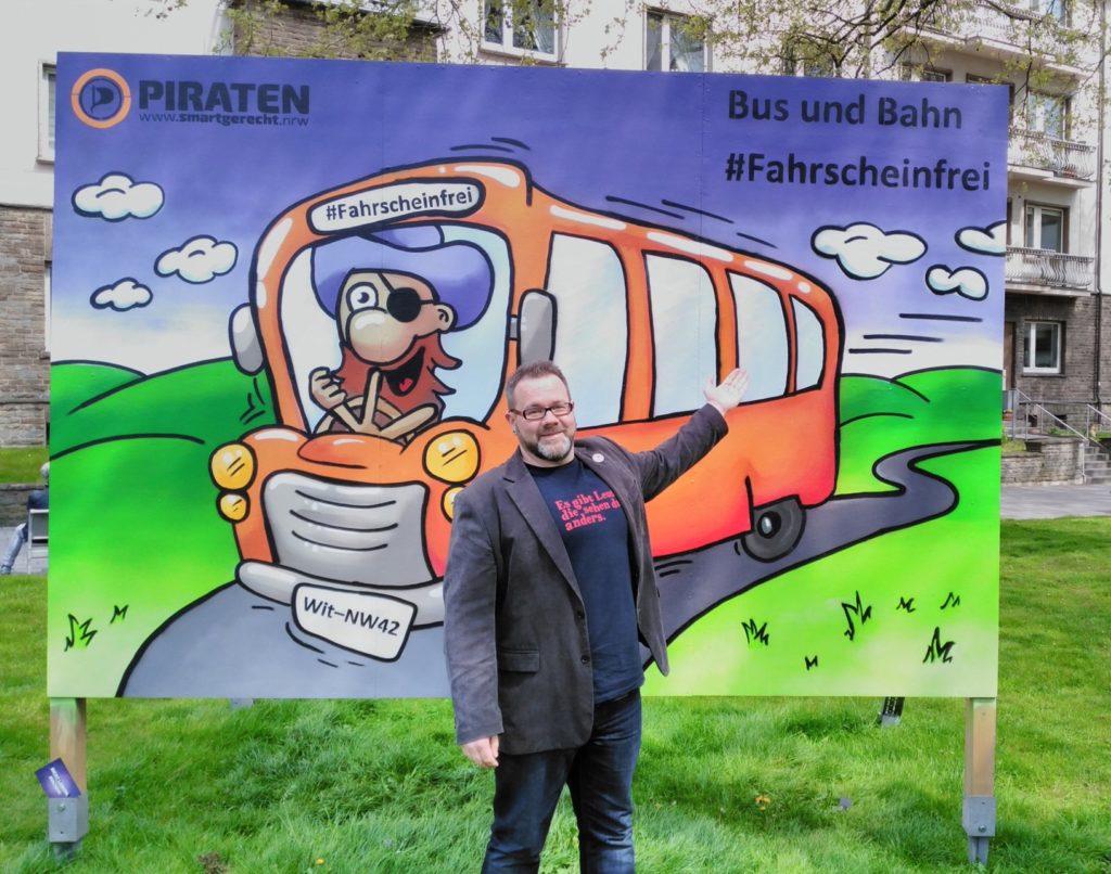 Stefan Borggraefe vor dem Streetart-Wahlplakat zum Thema „Bus & Bahn fahrscheinfrei“ in Witten