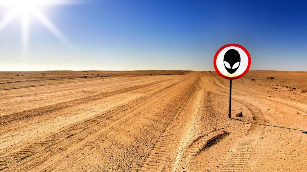 Bild einer Wüste mit einem Verkehrsschild „Achtung Aliens“