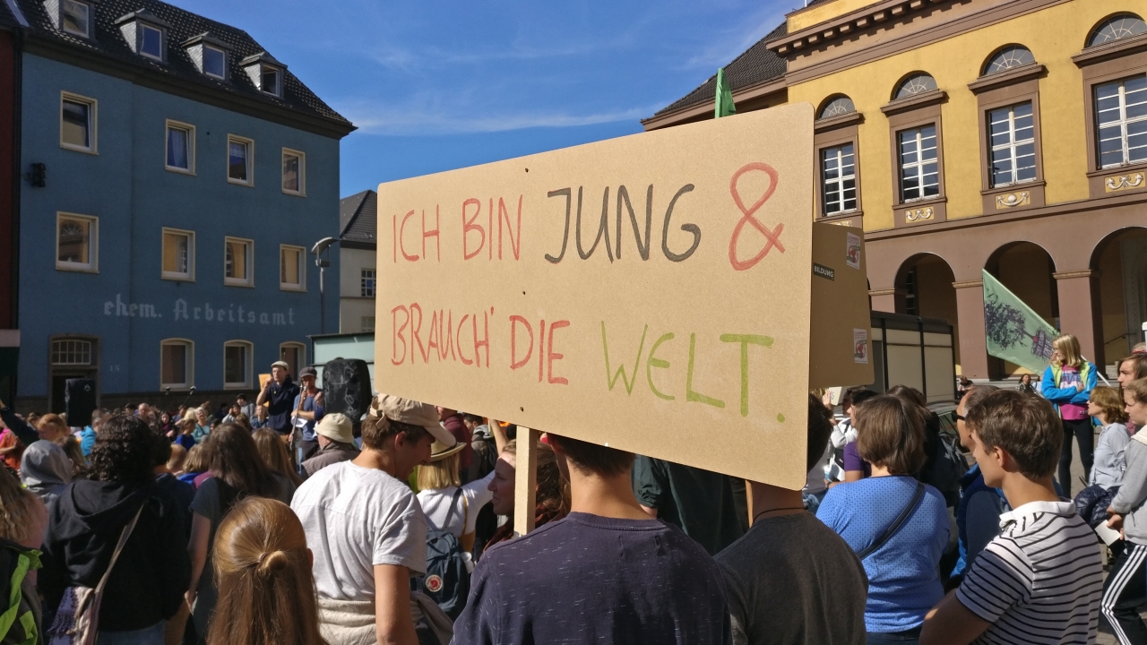 Foto von der Fridays for Future-Demo in Witten vom 20.09.2019. Im Vordergrund ein Demonstrant mit einem Schild, auf dem steht „Ich bin jung & brauch die Welt.“