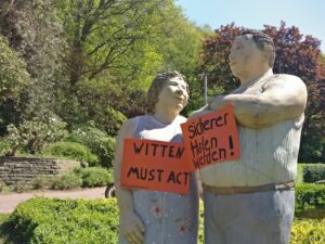 Lechner-Figuren im Wittener Stadtrat mit Schildern, die fordern, dass Witten Sicherer Hafen wird
