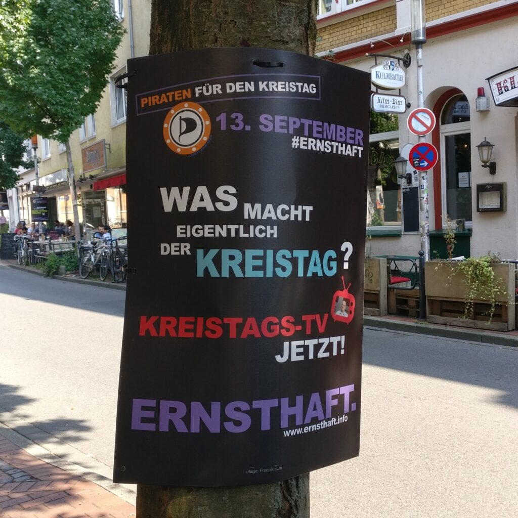 Wahlplakat der Piratenpartei Ennepe-Ruhr aus dem Kommunalwahlkampf 2020 hängt im Wittener Wiesenviertel. Darauf steht zu lesen „Was macht eigentlich der Kreistag? Kreistags-TV jetzt! Ernsthaft.”